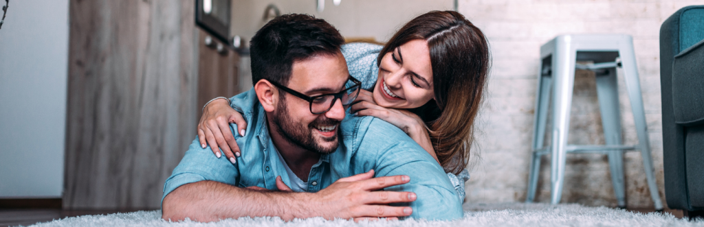 woman lies on man back talking enjoying happy moments together on white fluffy carpet