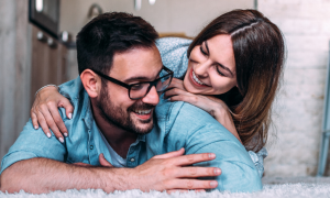 woman lies on man back talking enjoying happy moments together on white fluffy carpet