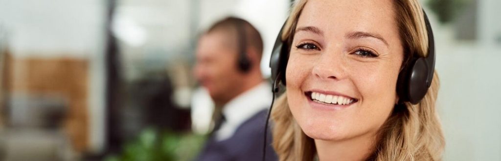 woman happily smiles wearing headphone sits in office
