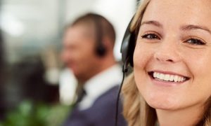 woman happily smiles wearing headphone sits in office