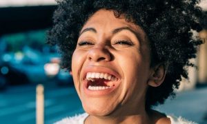 curly black hair woman happy face walks in car park laughing