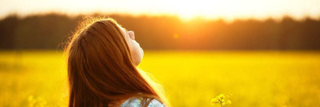 young woman heads up enjoying sunlight nature in canola field