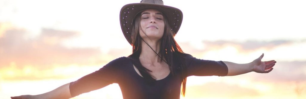 woman wears hat eyes closed gratitude life in sunset