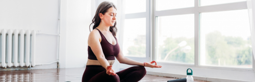 woman closes eyes focuses on breathing practicing meditation in peaceful living room