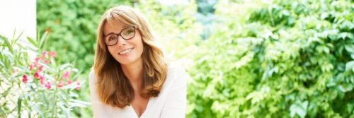 woman wearing prescription glasses smiling sitting in beautiful garden