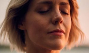 short hair woman eyes closed focuses on breathing meditation