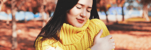 woman wearing yellow scarf eyes closed arms crossed enjoying gratitude life in park
