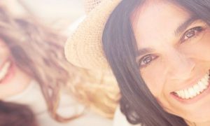 two women wears brown hats happily smiles in shiny sky