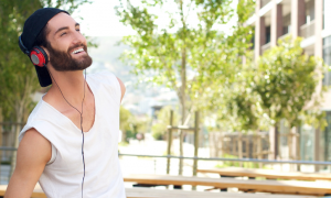 man with white sleeveless shirt wears headphone smiles looks at sky in quiet park