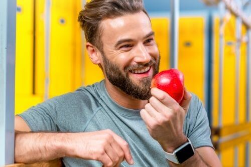 Healthy young man eating a delicious red apple