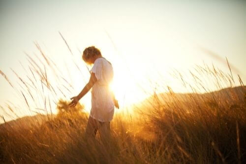 woman walking grass sunset sunrise nature peaceful regenerative life adventure connected natural touch
