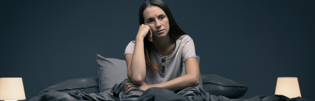 woman hand on face tiredly sits on bed lamps on experiences insomnia