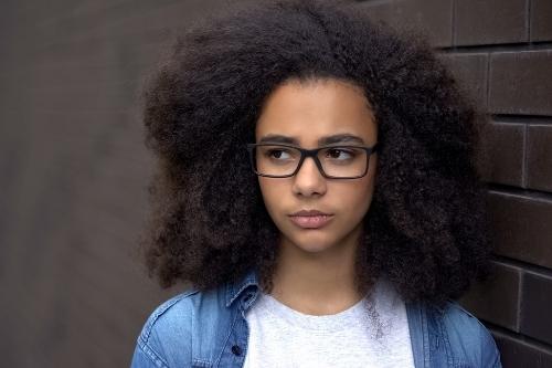 Thoughtful african schoolgirl brick wall background, awkward age insecurities