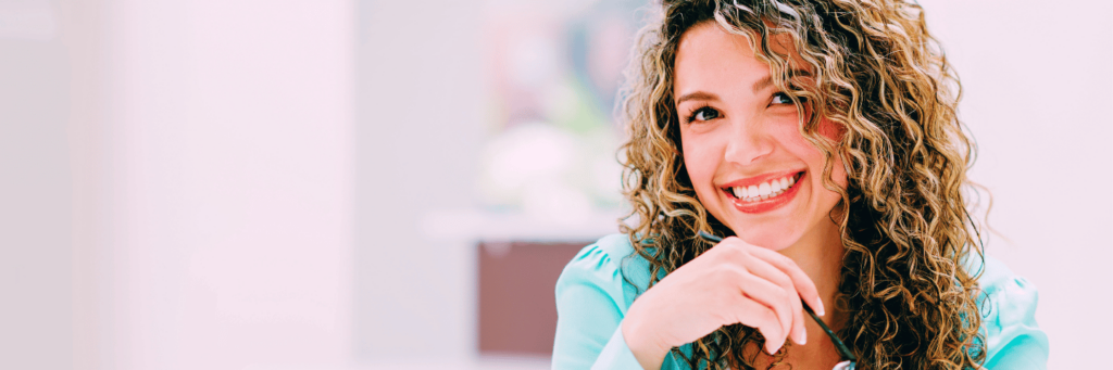 Woman with curly blonde hair smiling as she knows how how to deal with stress