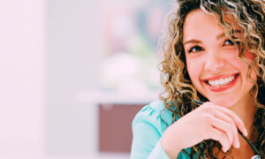 Woman with curly blonde hair smiling as she knows how how to deal with stress