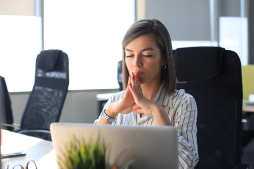 Calm beautiful businesswoman meditating in office with eyes closed