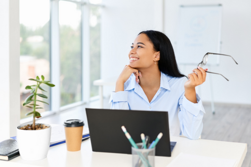 Smiling pretty businesswoman posing at her desk in a bright modern office with copy space. business success,  break time concept