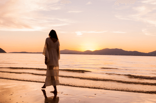 Woman walking along beach in golden sunlight