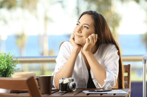 Happy woman dreaming at her desk with a camera