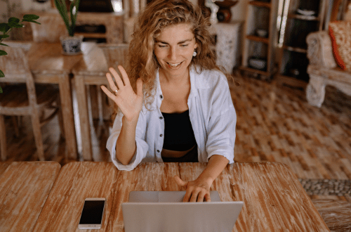 Woman with blonde hair and a laptop, raising her hand to say no to extra work