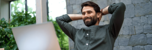 A man relaxing happily at his desk, an example of what it looks like to master your day