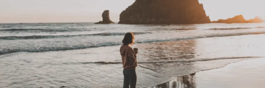 Woman on beach with coffee
