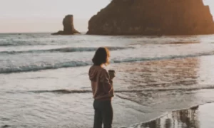 Woman on beach with coffee