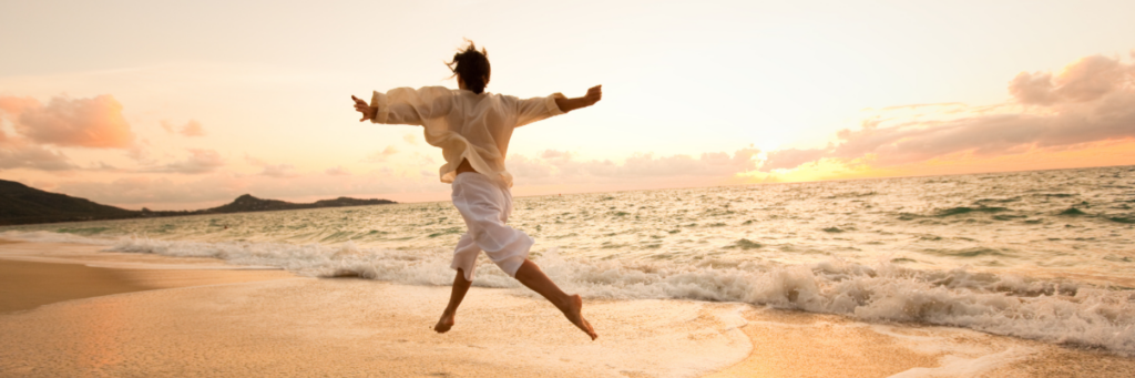 Person leaping joyfully on golden beach