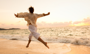 Person leaping joyfully on golden beach