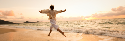 Person leaping joyfully on golden beach