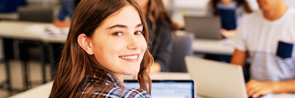Student smiling while studying at a calm desk, illustrating self-care for students and balanced study habits."