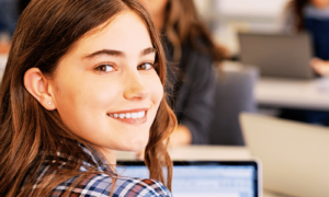 Student smiling while studying at a calm desk, illustrating self-care for students and balanced study habits."