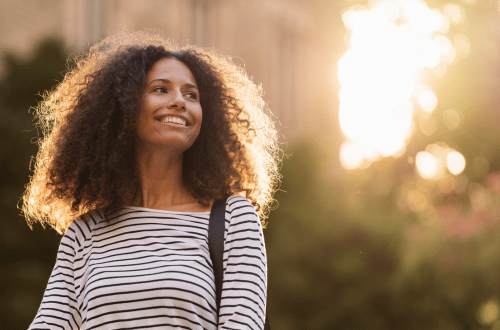 A woman in a striped top and curly hair stepping into her true empowerment.
