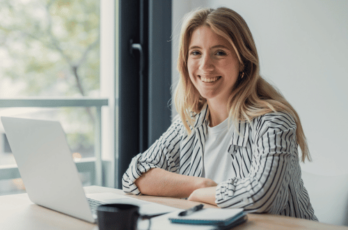 Happy woman at work, not exhibiting emotional exhaustion signs, as she's taken care of herself and knows the right strategies 