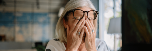 A woman sitting on her sofa with her eyes closed and her head resting on her hand, showing emotional exhaustion signs