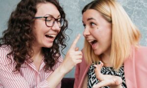 Two friends laughing together at a cafe table, each feeling truly seen
