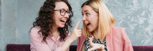 Two friends laughing together at a cafe table, each feeling truly seen