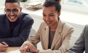 Three colleagues laughing together at a meeting table, a respectful team free of workplace incivility