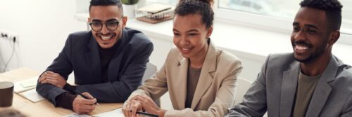 Three colleagues laughing together at a meeting table, a respectful team free of workplace incivility
