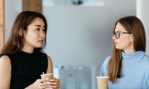 A manager and colleague talking calmly over coffee, working through job demands together