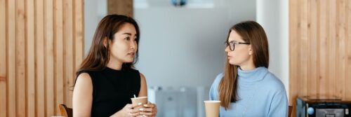 A manager and colleague talking calmly over coffee, working through job demands together