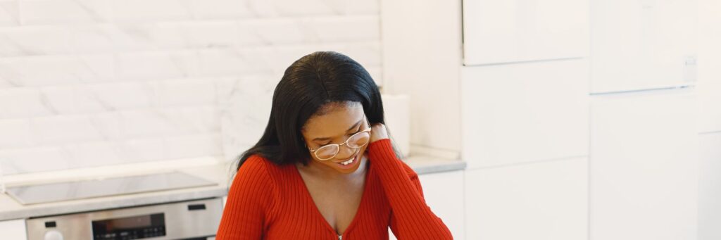 A woman in her forties smiling as she cooks in a bright modern kitchen, showing what an evening looks like without decision fatigue