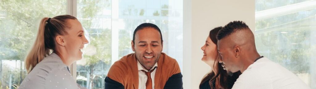 Colleagues in their forties smiling together in a sunlit meeting room, showing a team free of workplace incivility