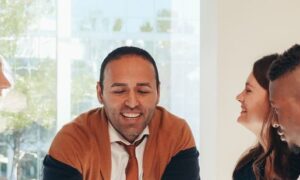 Colleagues in their forties smiling together in a sunlit meeting room, showing a team free of workplace incivility