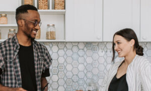 A couple in their forties smiling and talking in a bright modern kitchen, showing what it looks like when trust issues in relationships have eased