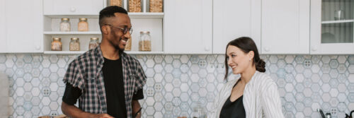 A couple in their forties smiling and talking in a bright modern kitchen, showing what it looks like when trust issues in relationships have eased