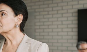 A woman in her fifties listening closely to a colleague across a meeting table in a bright modern office