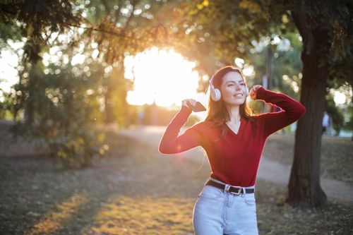 A woman walking outdoors at golden hour looking relaxed and happy, showing recovery from chronic stress effects