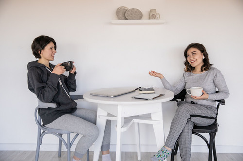 Two women in conversation in a bright room, showing the support that helps ease fear of failure