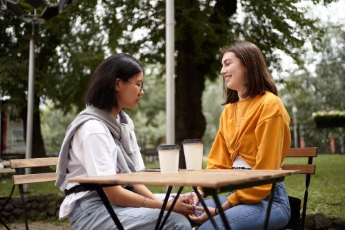Two friends in their forties talking warmly over coffee in golden light, showing how support helps with chronic stress effects
